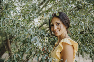 Mature woman standing under willow tree - MFF06293