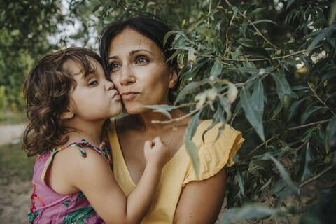 Mother and daughter embracing each other under willow tree stock photo