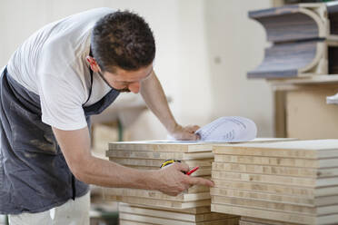 Man counting wood plank while working at workshop - EIF00268