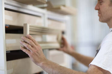 Man fitting frame in drawer while standing at workshop - EIF00270