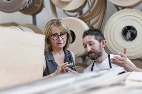 interior designer examining log while standing by coworker at workshop stock photo