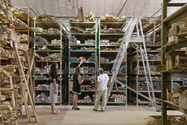 Angestellter und Kollege wählen eine verzierte Holzplatte aus, während sie in einem Lagerhaus in einer Fabrik stehen - EIF00288