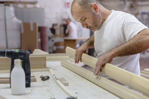 Carpenter applying glue on wood while working at workshop stock photo