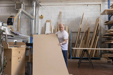 Mann, der eine Holzschneidemaschine bedient, während er in einer Fabrik steht - EIF00295