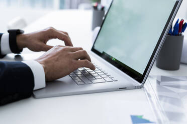 Hände eines männlichen Berufstätigen, der an einer Laptop-Tastatur am Arbeitsplatz festhält - GIOF09049