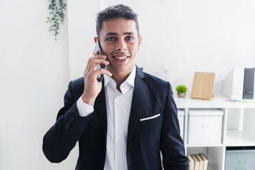 Confident young businessman talking on phone at creative office - GIOF09071