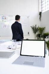 Laptop mit leerem Bildschirm auf dem Schreibtisch gegen männliche professionelle Planung Strategie am Arbeitsplatz - GIOF09076