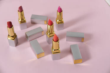 High angle of luxury lipsticks of various colors placed on pink background in studio - ADSF16605