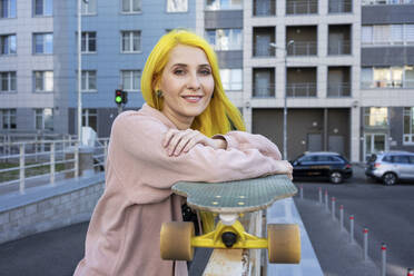 Junge Frau mit Skateboard steht auf der Straße in der Stadt - VPIF03114