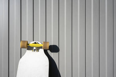 Skateboard kept against metal wall on sunny day - VPIF03133