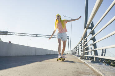 Woman enjoying while skating on skateboard during sunny day - VPIF03149