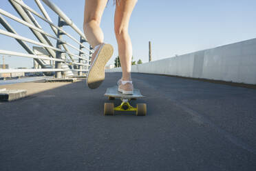 Beine einer Frau beim Schlittschuhlaufen auf einer Brücke an einem sonnigen Tag - VPIF03155