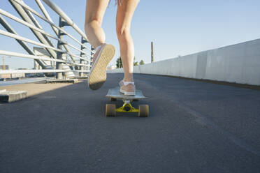 Legs of woman skating on bridge during sunny day - VPIF03155