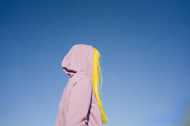 Woman looking away while standing against clear sky on sunny day - VPIF03171