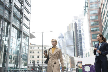 Businesswoman looking at colleague walking on road in city - PMF01332