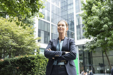 Businesswoman with arms crossed standing at office park - PMF01356