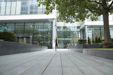 Woman walking with shopping clothes at office park - PMF01392