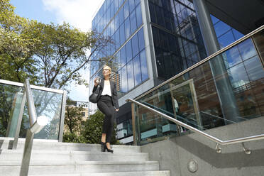 Woman looking away while walking on staircase against building - PMF01412