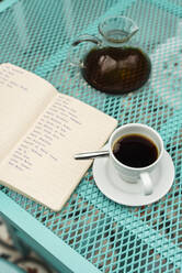 High angle view of book, coffee cup and pot kept on table - JMPF00448