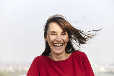 Mature woman laughing while standing against clear sky - FMKF06480
