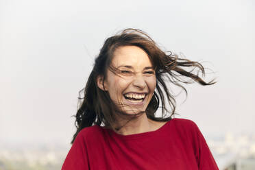 Cheerful woman standing against clear sky - FMKF06481