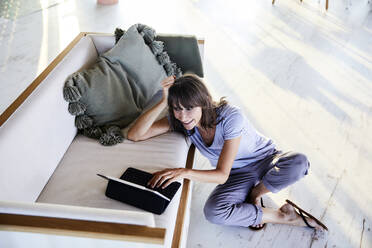 Mature woman with hands in hair using digital tablet at home - FMKF06521