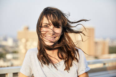 Reife Frau mit wehenden Haaren auf der Terrasse eines Gebäudes stehend - FMKF06522