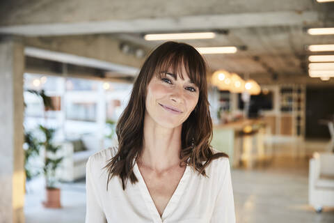 Brown hair mature woman smiling while standing at home stock photo