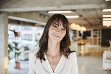 Brown hair mature woman smiling while standing at home - FMKF06532