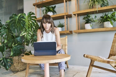 Woman using digital tablet while sitting at home - FMKF06577