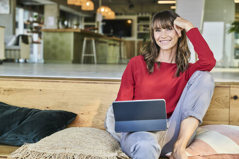 Woman using digital tablet while sitting at modern office - FMKF06599