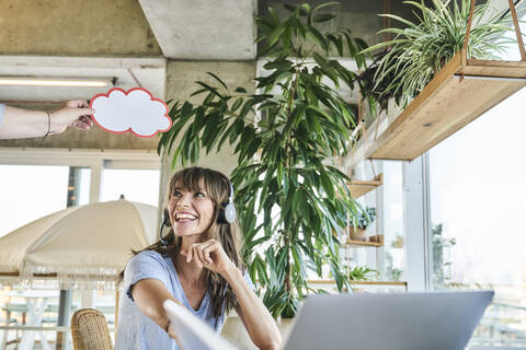 Smiling woman looking at female holding cloud paper cut on  stock photo