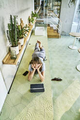 Woman lying on table while using digital tablet at home - FMKF06624