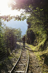 Man hiking along Tracciolino railroad track at sunset - MAMF01346