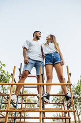 Young couple standing together on jungle gym - MIMFF00248