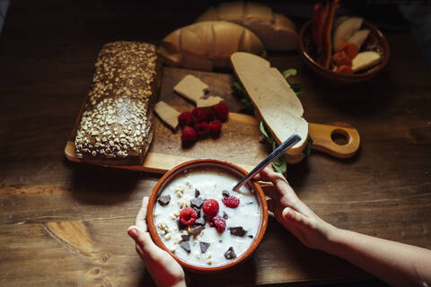 Girl hand holding bowl garnish with fruit on kitchen counter at home stock photo