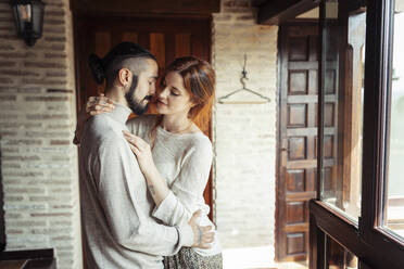 Couple doing romance while standing by window at home - JSMF01836