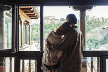 Couple with arm around standing by window at home - JSMF01889