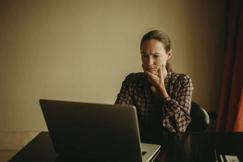 Serious businesswoman working on laptop in office stock photo