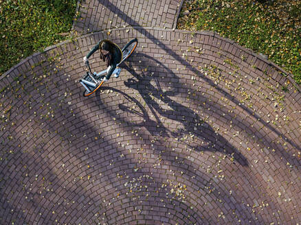 Luftaufnahme einer jungen Frau beim Fahrradfahren im Herbstpark - KNTF05724