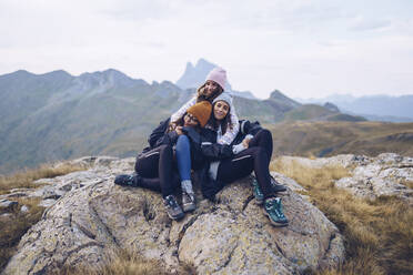 Friends embracing while sitting on rock around Ibones of Anayet - RSGF00361