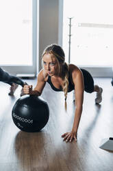 Junge Frau trainiert mit Fitnessball im Fitnessstudio - MPPF01144