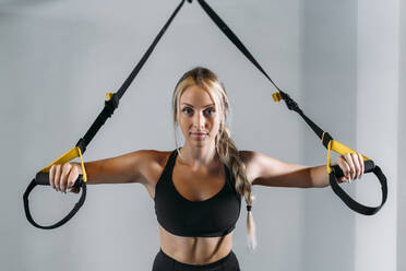 Junge Sportlerin bei der Vorbereitung auf das Suspensionstraining im Fitnessstudio - MPPF01150