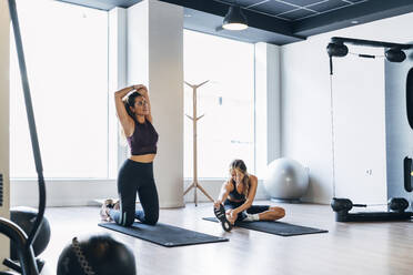 Weibliche Athletin bei Dehnungsübungen im Sitzen im Fitnessstudio - MPPF01157