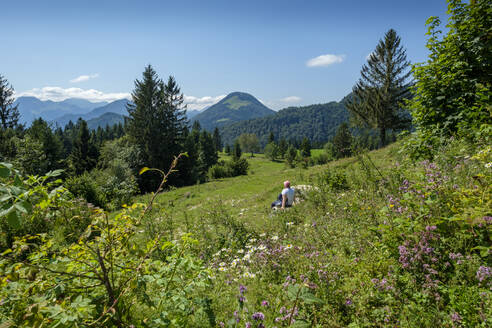 Ältere Frau entspannt sich im Sommer auf einer Bergwiese - LBF03250