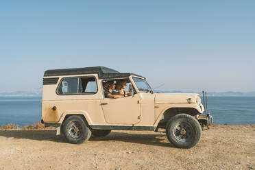 Man and woman sitting in car at beach - DAMF00560