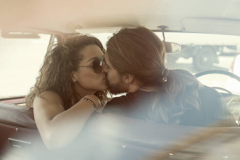 Junges Paar küsst sich auf die Lippen, während es im Auto sitzt - AJOF00214