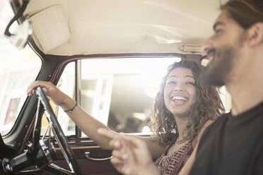 Young woman laughing while driving car with male friend on sunny day - AJOF00218