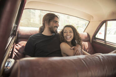 Young couple laughing while relaxing in car on sunny day - AJOF00220