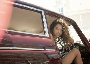 Young woman sitting in car on sunny day - AJOF00222